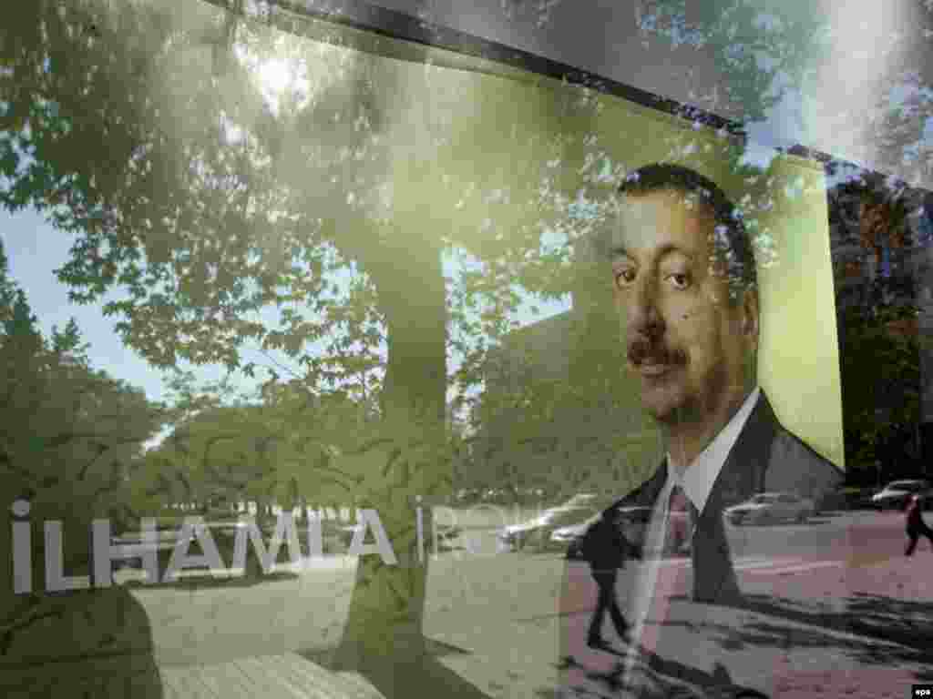 epa01519158 Azeri peoples are reflected in the glass of a window shop with a pre-electoral poster of candidate and present President of Azerbaijan Ilkham Aliyev in Baku, Azerbaijan, 13 October 2008. Seeped in oil wealth and in the cross hairs of a regional power struggle between the US and Russia, Azerbaijan votes on 15 October to reelect President Ilham Aliyev, whose only real opponents will be boycotting the polls. Aliyev, 46, replaced his strongarm father Heydar Aliyev in 2003. Obeservers say there is as good as no chance the coming election will break the 35 years of dynastic rule over the Caspian state.