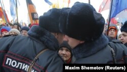 Russia - A woman looks at Russian police officers as they talk during a festive concert marking the second anniversary of Russia's annexation of the Crimea region, in Red Square in central Moscow, Russia, March 18, 2016.