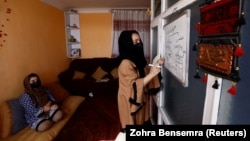 آرشیف، دو خواهری که در خانه درس های مکتب را مرور می کنند