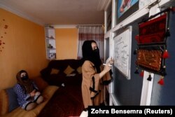 Sahar, 17, an 11th grader, copies lessons from YouTube onto a whiteboard while her sister, Sewita, 19, looks on, at their home in Kabul on October 19.