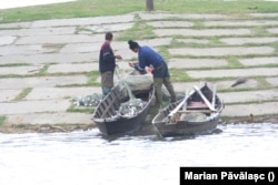 Doi pescari își împart recolta de pește prins din Dunăre.