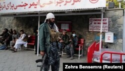 Taliban fighters wait as they come to check on injured comrades at the entrance of the military hospital in Kabul on November 2.