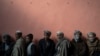 Men wait in a line to receive cash at a money distribution organized by the World Food Program in Kabul.