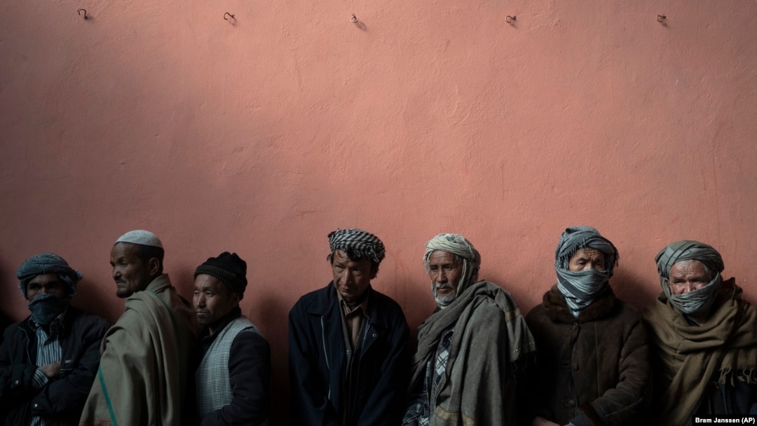 Men wait in a line to receive cash at a money distribution organized by the World Food Program in Kabul.