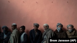 Men wait in a line to receive cash at a money distribution organized by the World Food Program in Kabul.