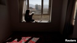دختری افغان که با بازگشت طالبان به قدرت از رفتن به مکتب محروم شده در خانه به مطالعه پرداخته است. 