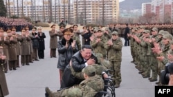 Udhëheqësi i Koresë së Veriut, Kim Jong Un, përqafon një ushtar në karrocë teksa mirëpret trupat koreanoveriroe nga misioni i tyre në Rusi, 12 dhjetor.