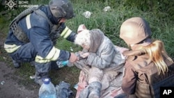 In this photo provided by the Ukrainian Emergency Services on May 8, a rescue worker helps an injured elderly woman evacuated from a building which was heavily damaged by a Russian strike in the Sumy region.