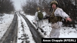 Soldații merg pe un drum înzăpezit în regiunea Luhansk din Ucraina, în decembrie 2021.