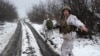 Український військовий відводить фотографа від потенційного снайперського вогню в Луганській області 7 грудня