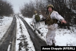 Солдат жестом показує фотографу триматися одного боку дороги, щоб не стати мішенню снайпера