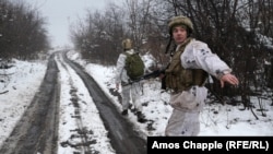 Ushtarët duke ecur në një rrugë me borë në rajonin e Luhanskut në Ukrainë në dhjetor të vitit 2021. 
