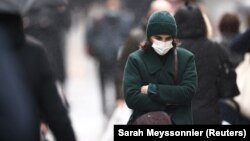 Një grua me maskë për mbrojtje kundër koronavirusit shihet duke ecur rrugëve të Parisit.