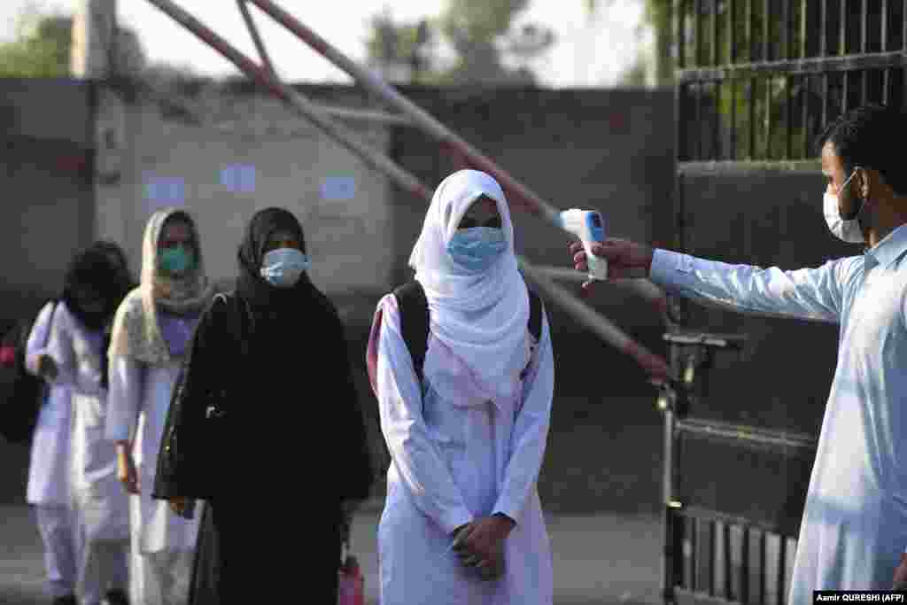A staff member checks the body temperature of students at the entrance to the Islamabad Model College of Commerce for Girls on September 15 after educational institutions were reopened nearly six months after the start of the COVID-19 pandemic.