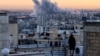 TOPSHOT - A person stands on the roof of a building looking at a plume of smoke rises after a strike on the Iranian capital Tehran, on March 3, 2026.