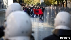 Demonstruesit shfaqin një flamur shqiptar para policëve të pajisur me mjete kundër trazirave, gjatë një proteste antiqeveritare nga studentët në Tiranë, Shqipëri, më 16 tetor 2026.