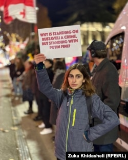 წარწერა ინგლისურად: რატომ არის რუსთაველზე დგომა დანაშაული, პუტინის გვერდით დგომა კი კარგი?