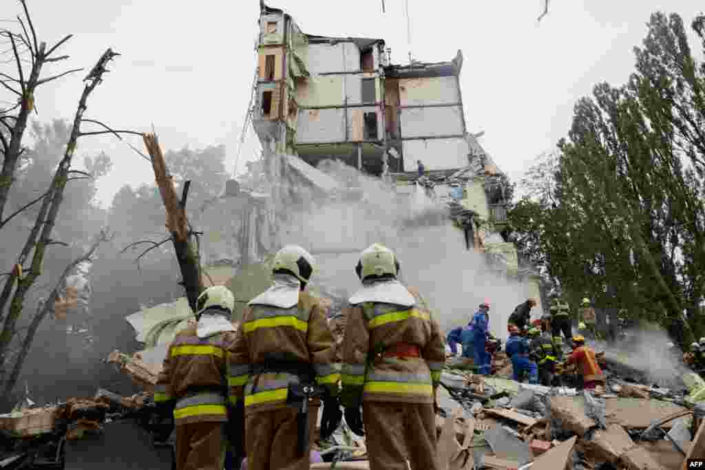 Ukrainian rescue workers clear debris as they work at the site of a destroyed residential building following a Russian air attack on Kyiv. 