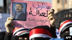 A Yemeni woman holds a sign bearing a doctored picture of President Ali Abdullah Saleh behind bars with text that reads, "Wanted for justice... The one who captures him will be rewarded," during a pro-democracy demonstration in Sanaa in late October.