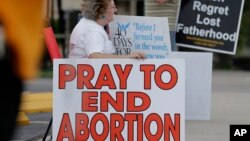 Žena sjedi pored natpisa: "Molite se za okončanje abortusa" u Teksasu, 