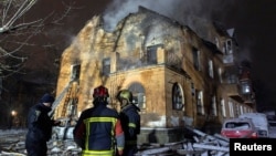 د اوکراين په پلازمېنه کييف کې اور وژونکي د روسيې په بريد کې د زيانمنې شوې ودانۍ مخ ته ولاړ دي ـ د جنورۍ نهمې انځور