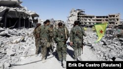 Syrian Democratic Forces troops walk past the ruins of destroyed buildings near the National Hospital in Raqqa on October 17.