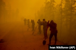 Volunteers pause while working at the scene of a forest fire near the Kyuyorelyakh village in the Gorny Ulus area west of Yakutsk, in Russia's vast Siberia region, on August 7, 2021.