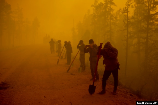 Volunteers pause while working at the scene of a forest fire near the Kyuyorelyakh village in the Gorny Ulus area west of Yakutsk, in Russia's vast Siberia region, on August 7, 2021.