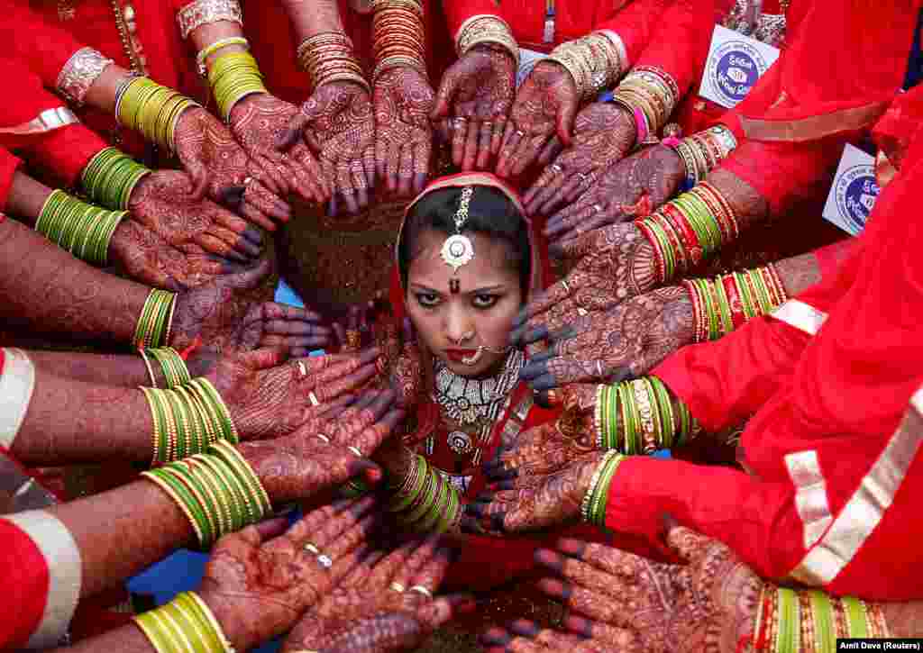 Brides display their hands decorated with henna around a bride as she poses for her own photographer during a mass marriage ceremony in which, according to its organizers, 70 Muslim couples took their wedding vows, in Ahmedabad, India. (Reuters/Amit Dave)