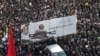 Iranian mourners carry a huge banner with poster of Qassem Soleimani and slogans reading in Persian "hard revenge is on the way". January 6, 2020