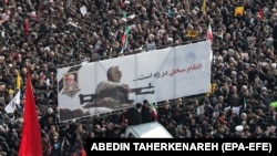 Iranian mourners carry a huge banner with poster of Qassem Soleimani and slogans reading in Persian "hard revenge is on the way". January 6, 2020