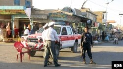 Afghan security officials stand guard near the site of a bomb blast in Kandahar on May 26.