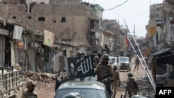 Pakistani soldiers patrol through a destroyed bazaar in the main town of Miran Shah, North Waziristan on July 9, 2014.