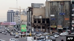 Vehicule trec pe lângă o clădire incendiată, distrusă în timpul protestelor publice din capitala iraniană Teheran, pe 19 ianuarie 2026.