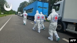 International Red Cross representatives walk past a convoy of refrigerator trucks carrying the bodies of Ukrainian soldiers being repatriated on June 11.