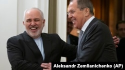 Russian Foreign Minister Sergei Lavrov (right) and Iranian Foreign Minister Mohammad Javad Zarif smile as they enter a hall for talks in Moscow on December 30.