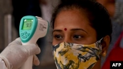 Социален работник мери температурата на жена в Индия. Снимката е архивна.