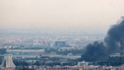 Smoke billows from a site near the Azadi Tower (L) in central Tehran, as fighting between Israel and Iran continues on June 16, 2025.
