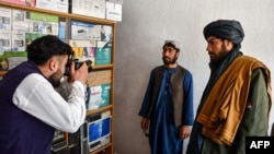 یک عکاس در حال گرفتن عکس یک عضو طالبان در شهر میمنه