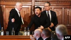 Președintele Camerei Comunelor, Lindsay Hoyle (stânga), și prim-ministrul britanic Keir Starmer (dreapta) stau în picioare după ce președintele Ucrainei, Volodimir Zelenski a terminat discursul susținut în fața membrilor Parlamentului britanic - Palatul Westminster, 17 martie