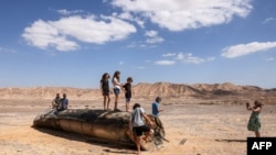 Ljudi stoje na ostatku iranske rakete u pustinji Negev blizu Arada, Izrael, 2. oktobra 2024.