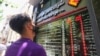 An Iranian man, wearing a protective mask, checks the currency exchange rates in Tehran, June 22, 2020