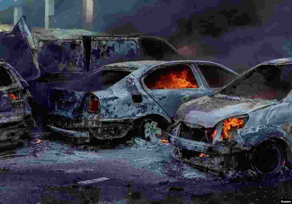 Cars burn at the site of the Russian air strike on Kharkiv.