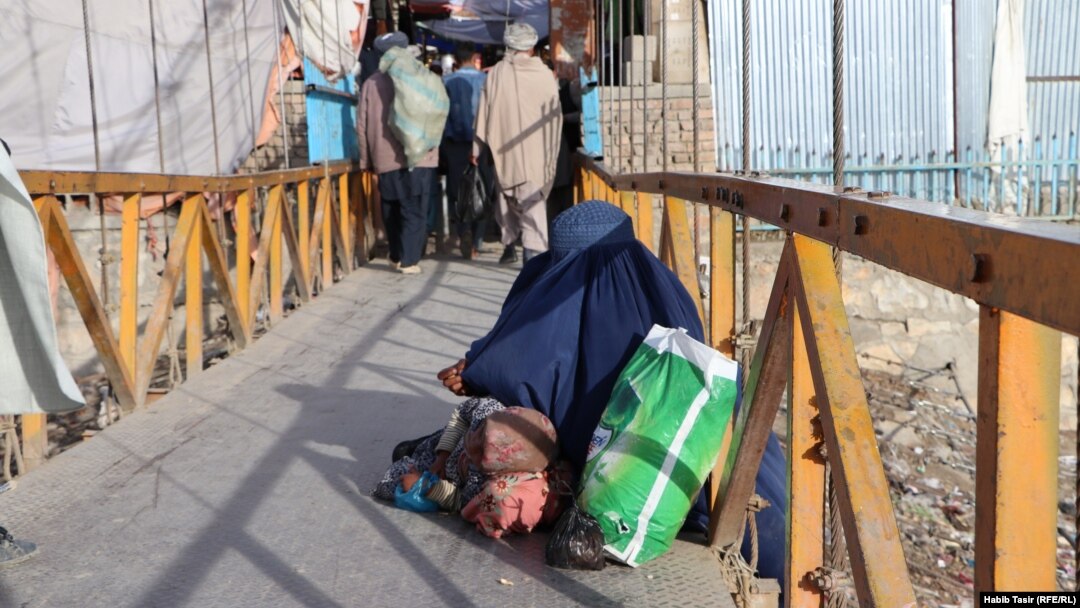A woman and child beg on a bridge in Ghazni.