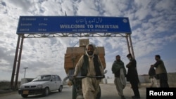 A Pashtun man passes a road sign while pulling supplies toward the Pakistan-Afghanistan border crossing in Chaman.