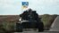UKRAINE – A Ukrainian tank rides with a flag picturing Ukraine and US flags shaking hands in Novostepanivka, Kharkiv region, on September 19, 2022