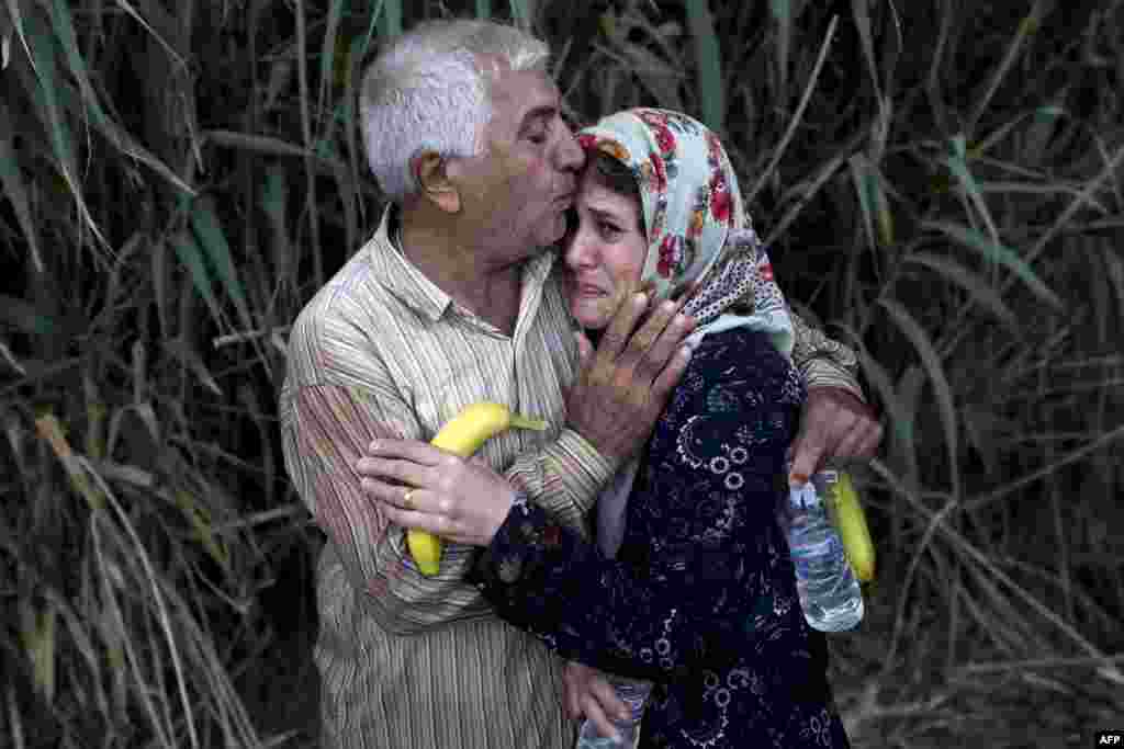 A migrant woman cries as she is embraced by a relative upon their arrival on the shores of the Greek island of Lesbos after crossing the Aegean Sea from Turkey on a dinghy. (AFP/Angelos Tzortzinis)