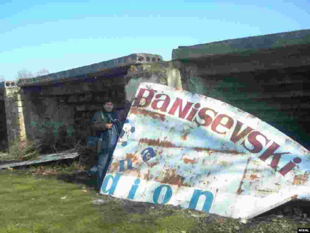 A reporter poses outside the crumbling soccer stadium in Masalli - While the new sports facilities stand empty, Azerbaijanis complain that there has been no state investment to reconstruct facilities that are actually in use, such as this soccer stadium, home to a second-tier league. 