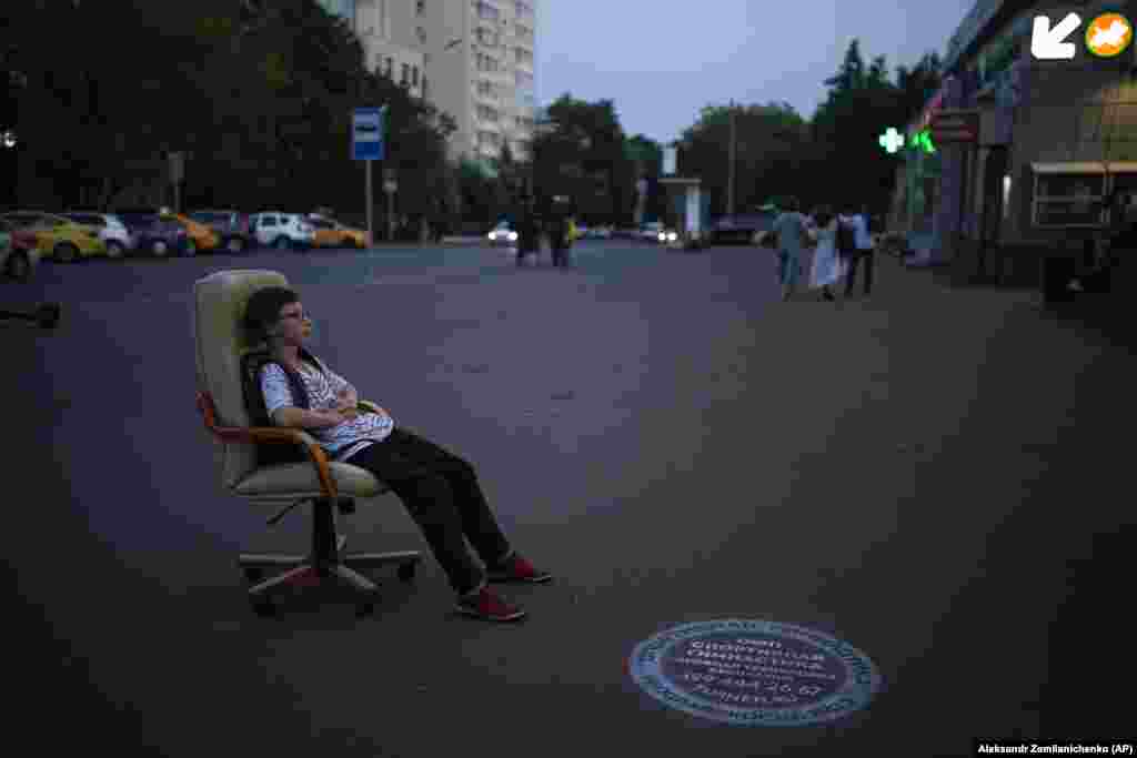 A Russian teenager rests after a hot day in a chair abandoned on a Moscow street.&nbsp;