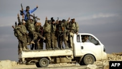 Fighters from the Arab-Kurdish alliance, known as the Syrian Democratic Forces, wave from a truck driving through on the western outskirts of the Islamic State bastion of Raqqa in Syria. (file photo)